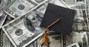 Graduation cap on top of pile of money to represent tuition collection.