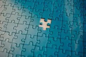 Close-up of interlocking blue jigsaw puzzle pieces with a missing piece creating an empty hole in the center area.