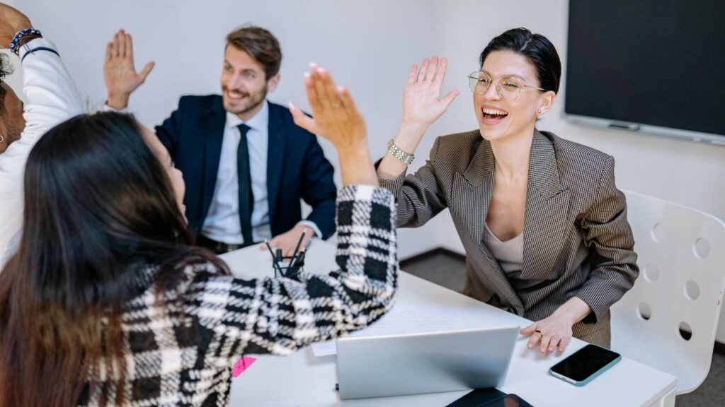 A group of professionals celebrate a success with high-fives in a meeting about collection services, fostering teamwork and positivity.