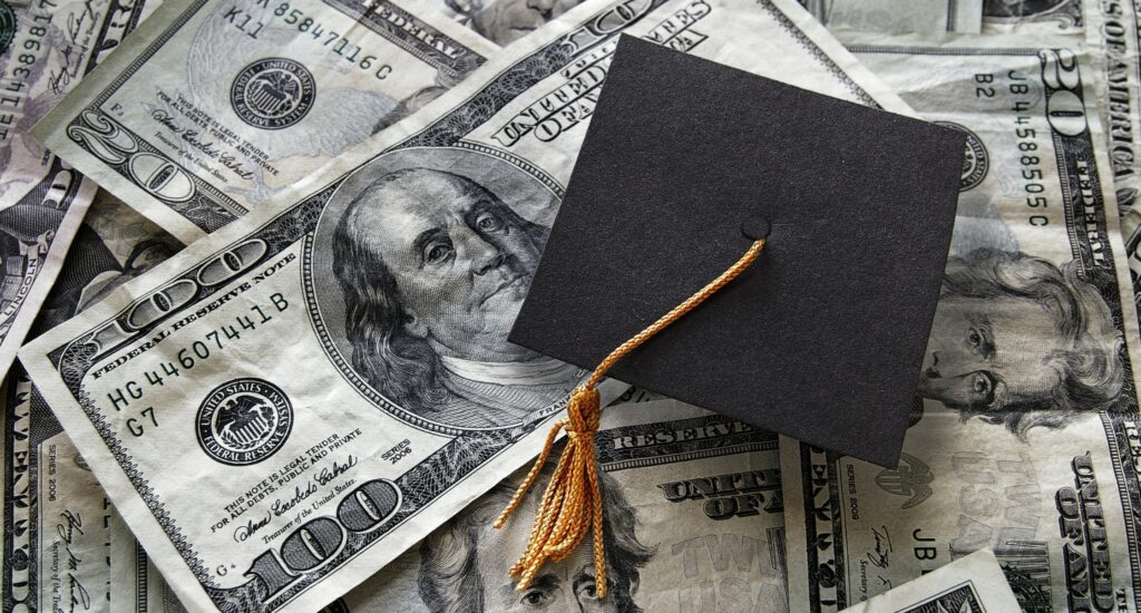 Graduation cap on top of pile of money to represent tuition collection.