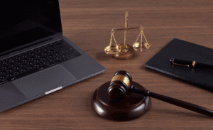 A laptop and a gavel on a desk, showing the choice between small claims court and hiring a collection agency.
