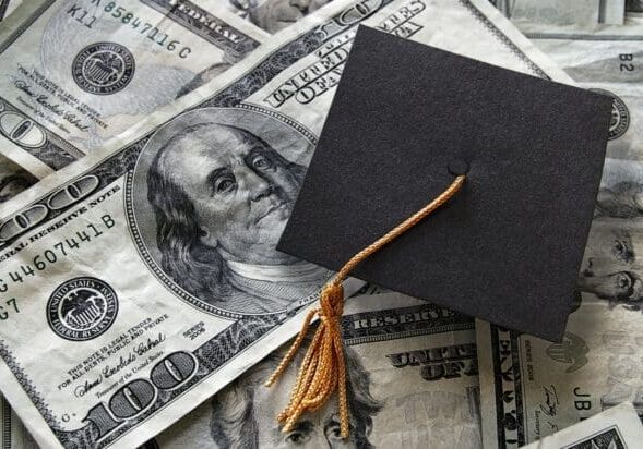 Graduation cap on top of pile of money to represent tuition collection.