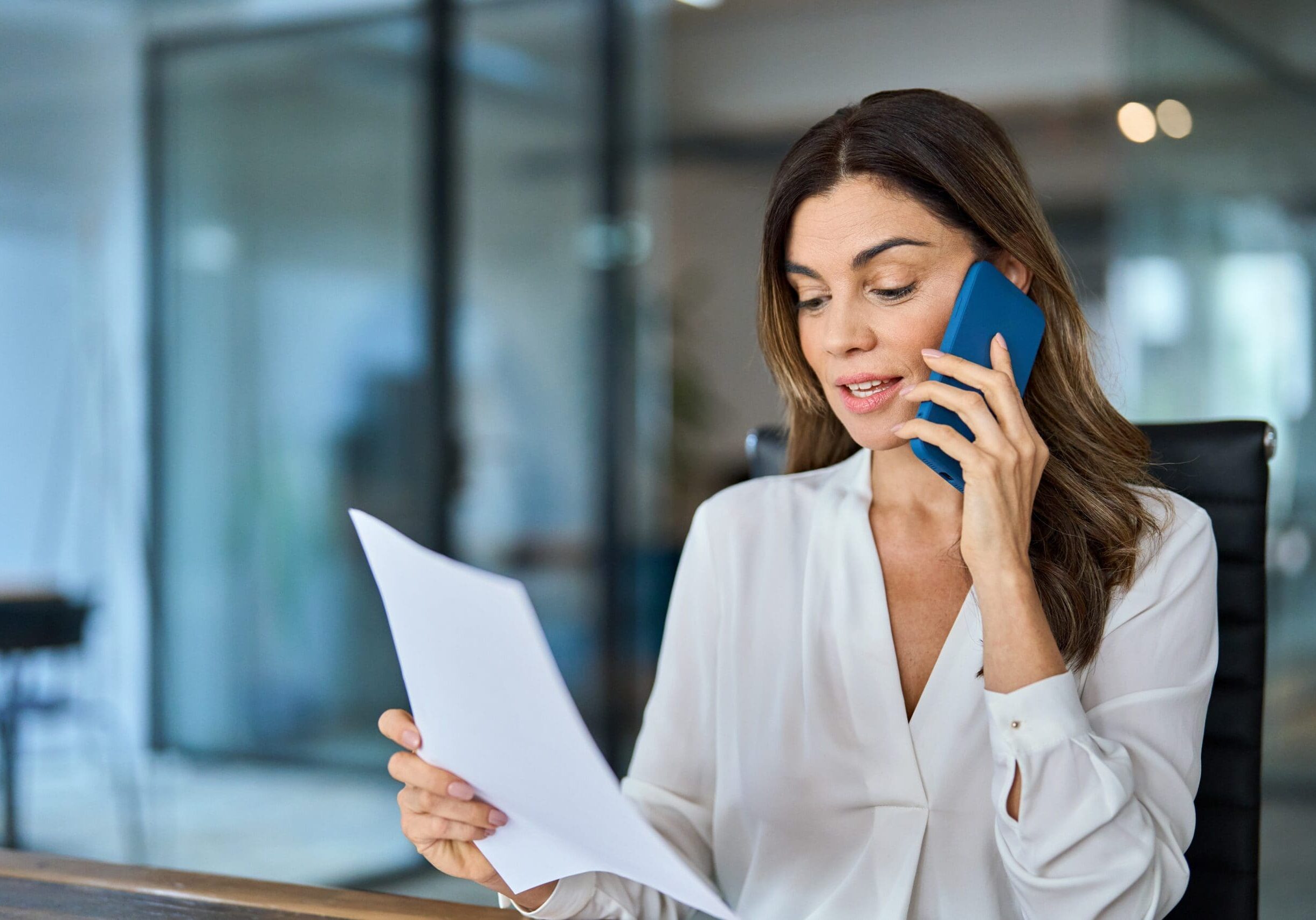 Collection company employee reviewing a document while speaking on the phone at a desk