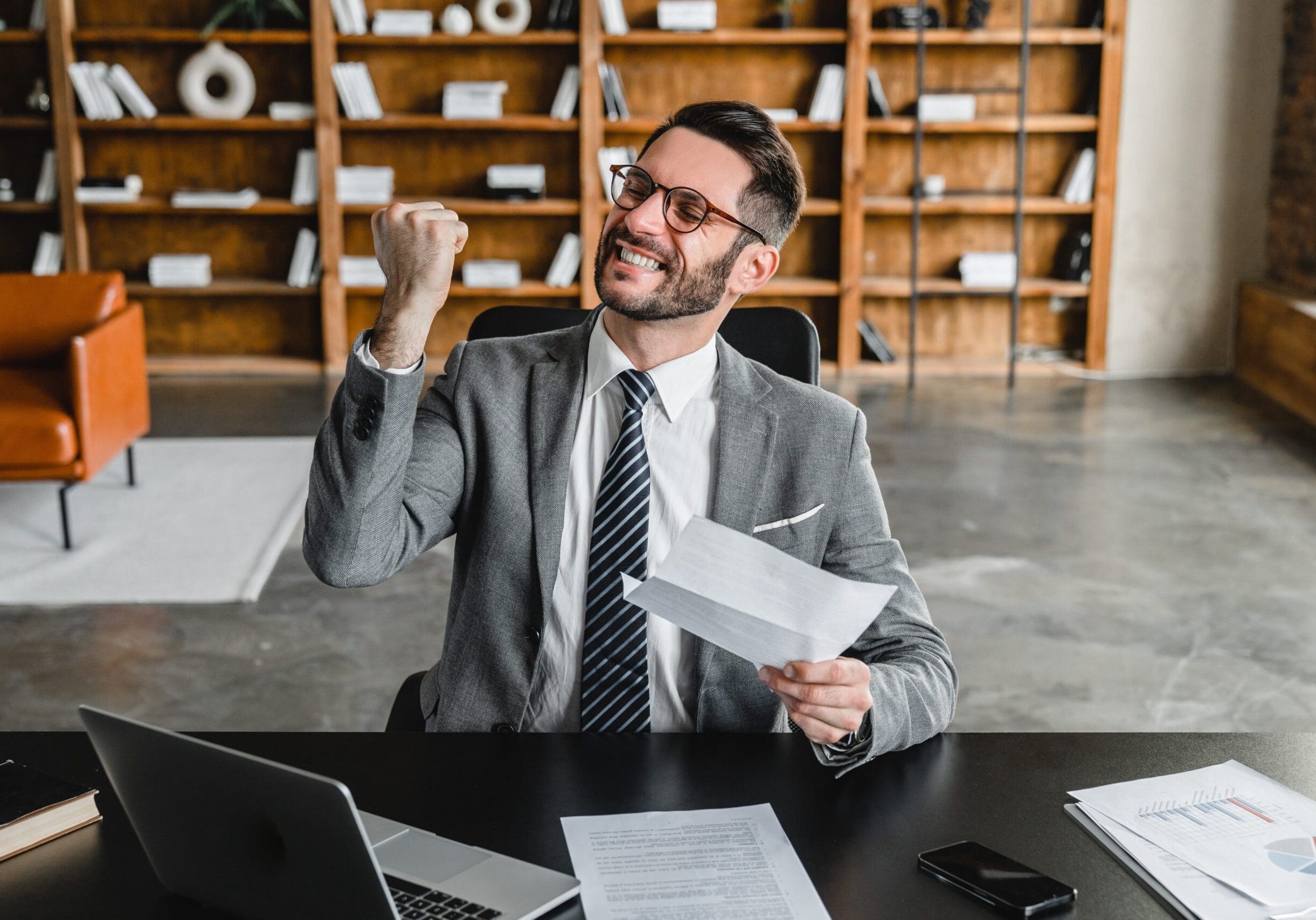 Professional smiling and raising a fist while reviewing a debt collection agency document at a desk