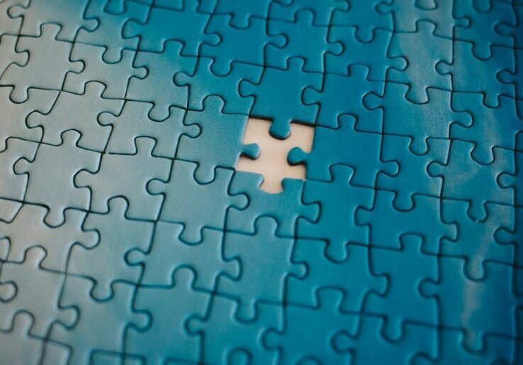 Close-up of interlocking blue jigsaw puzzle pieces with a missing piece creating an empty hole in the center area.